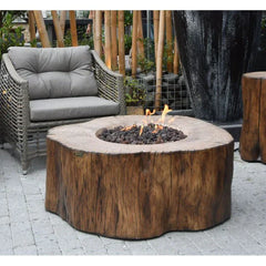 Manchester rustic wood-look outdoor fire pit with flames, next to wicker patio chair