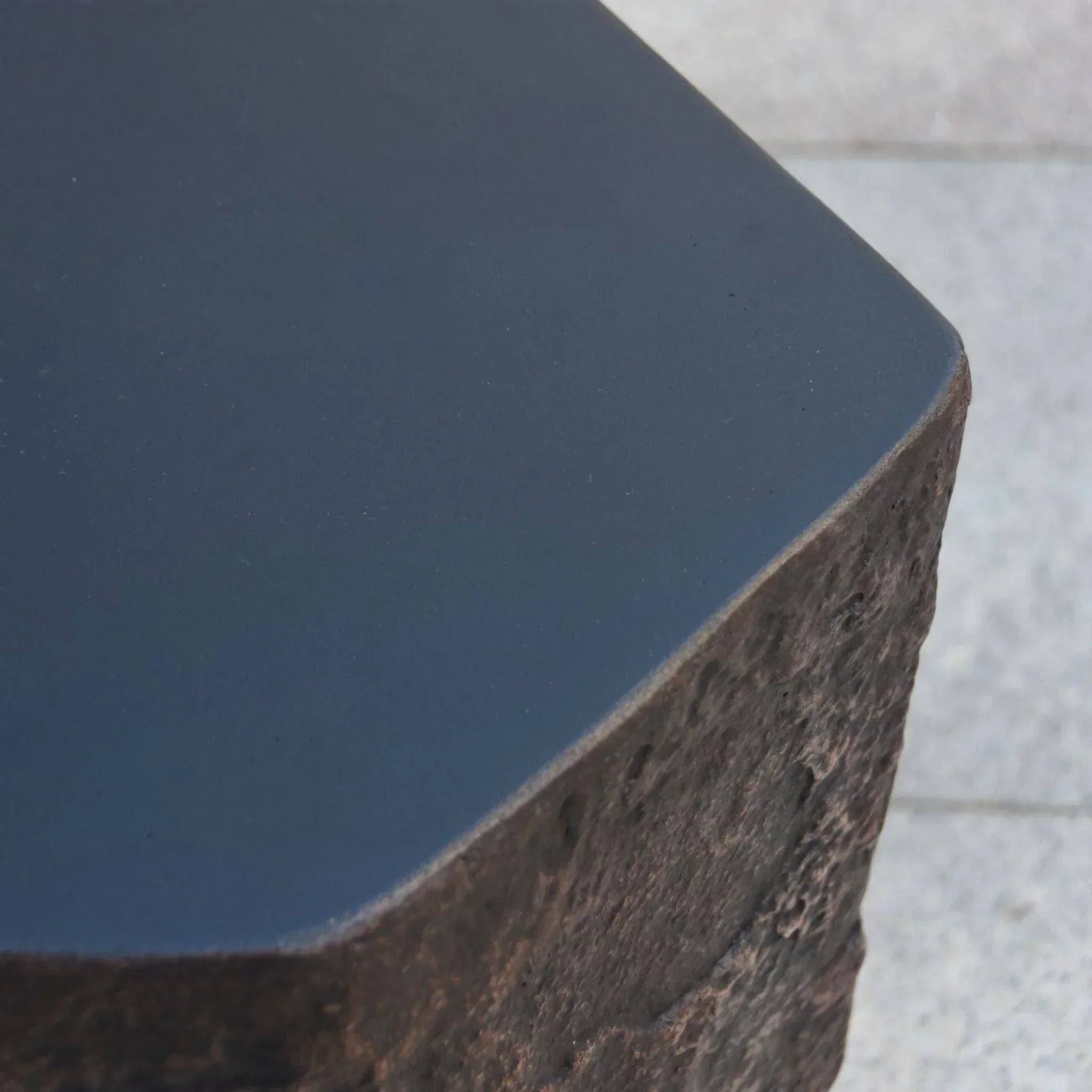 Elementi Columbia Seat close-up with textured stone and smooth black surface, outdoor accessory.