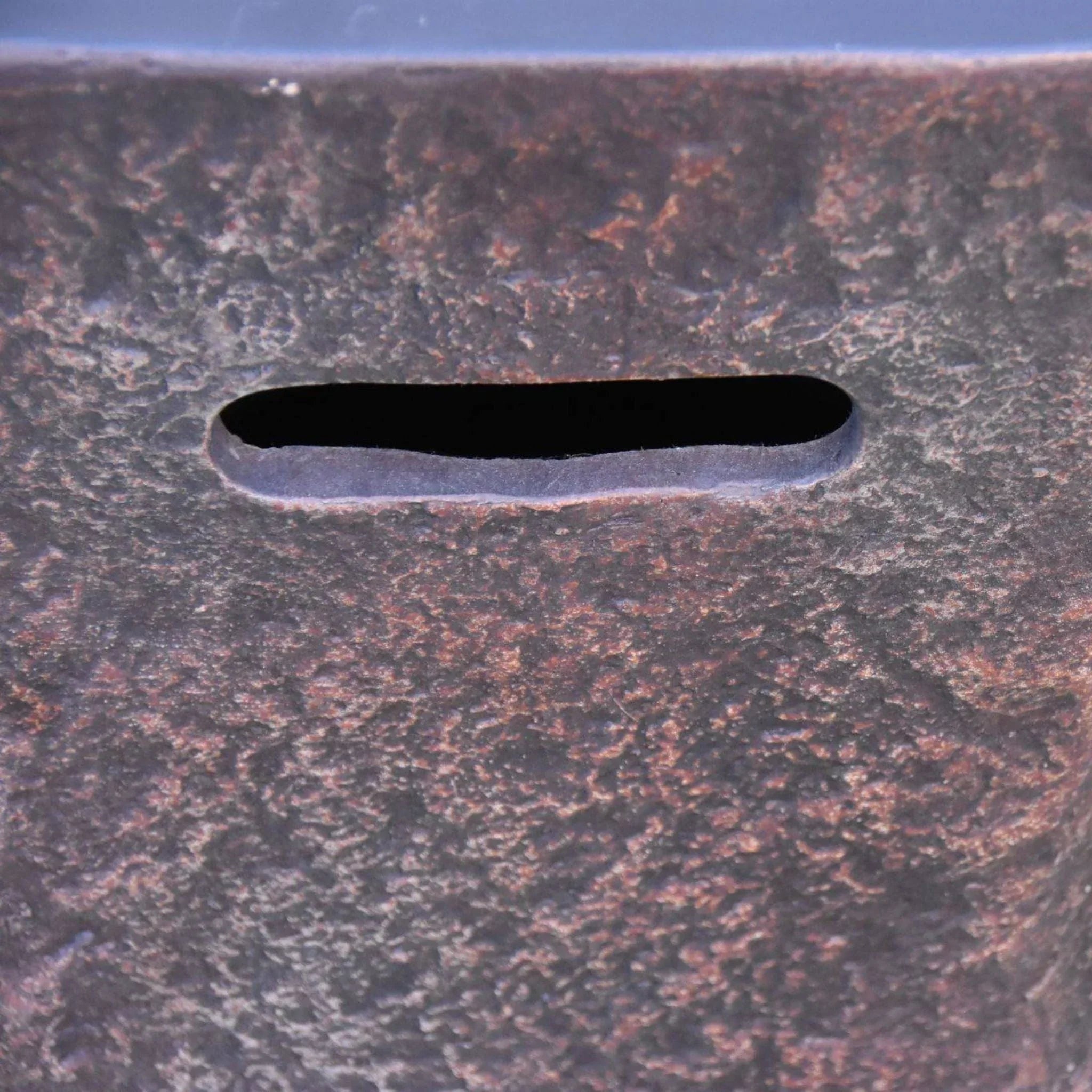 Elementi Columbia rust-textured metal seat detail with oval slot opening