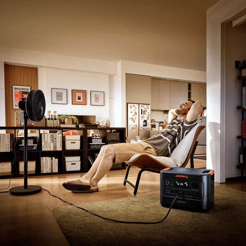 Jackery portable power station powering a fan in a modern living room with a relaxed man