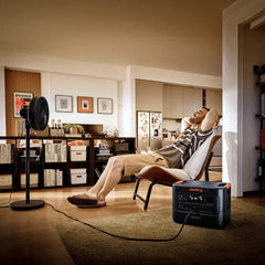 Jackery portable power station powering a fan in a modern living room with a relaxed man
