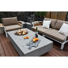 Metropolis modern outdoor fire pit table set with beige cushioned sofas, wine, and fruit
