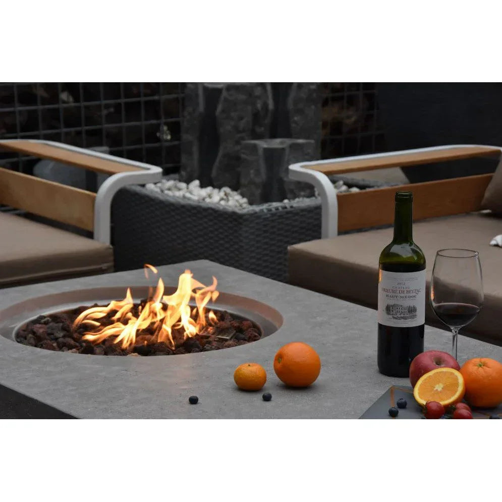 Bottle of red wine, fruit, and fire pit on a modern outdoor patio table with seating
