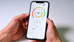Battery monitoring app showing 100% charge on smartphone screen in hand