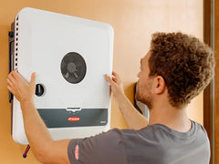 Fronius wall-mounted solar inverter being installed by a man, energy equipment